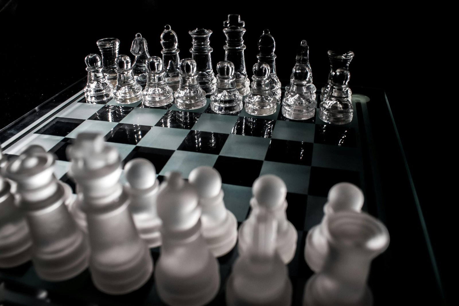 Close-up of frosted and clear glass chess pieces on a chessboard, symbolizing strategy and intelligence.